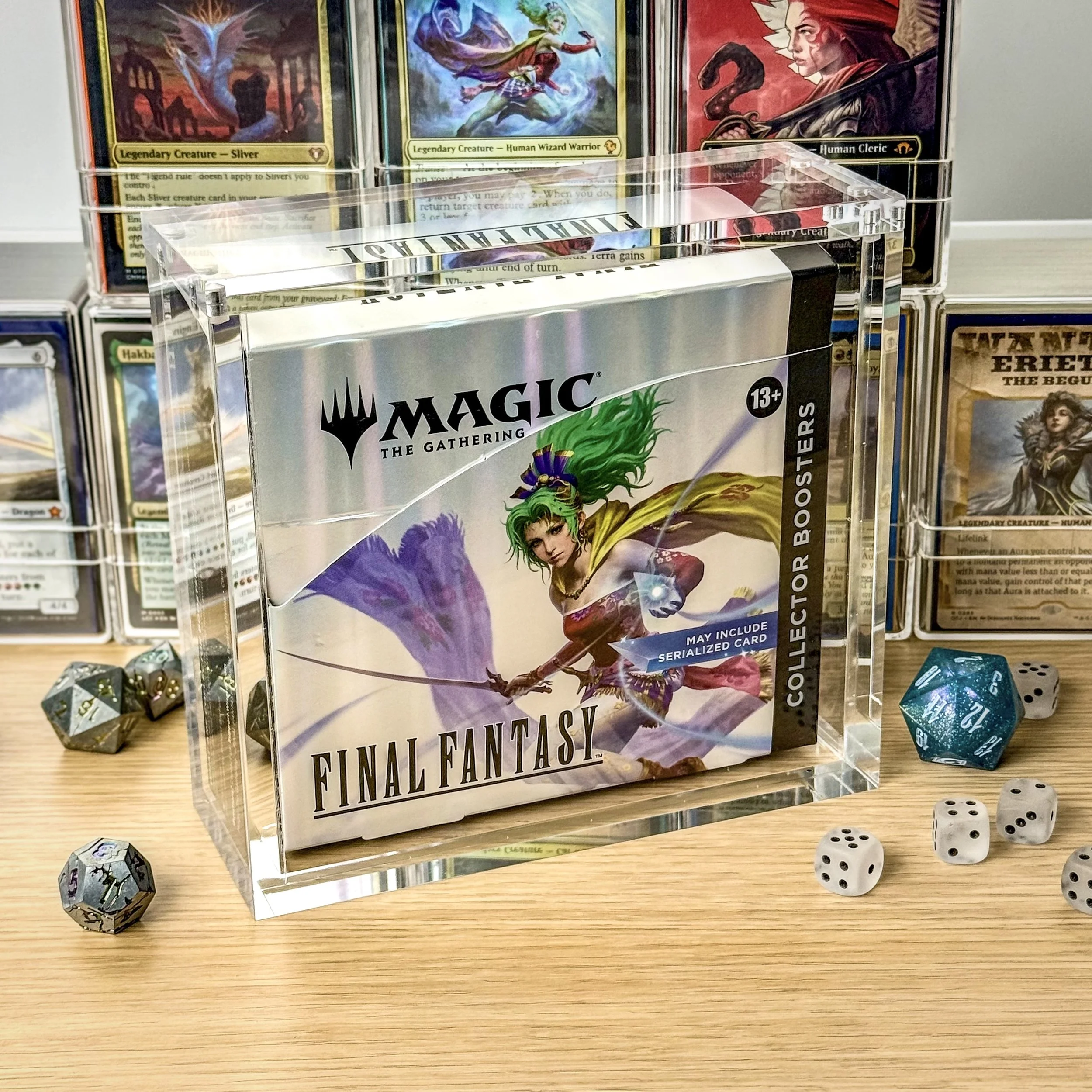 A collector's edition box of Magic: The Gathering FINAL FANTASY set featuring a female character with green hair, holding a purple flag, with several dice around it on a wooden surface and card binders in the background.