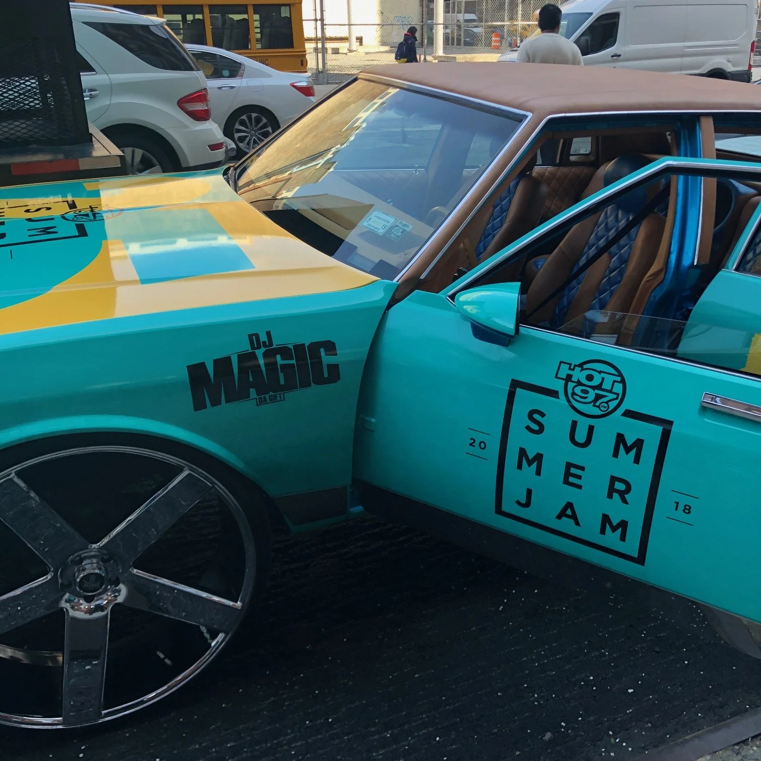 A colorful sports car with logos for Hot 97 Summer Jam and DJ Magic, parked on a street with other vehicles and pedestrians visible in the background.