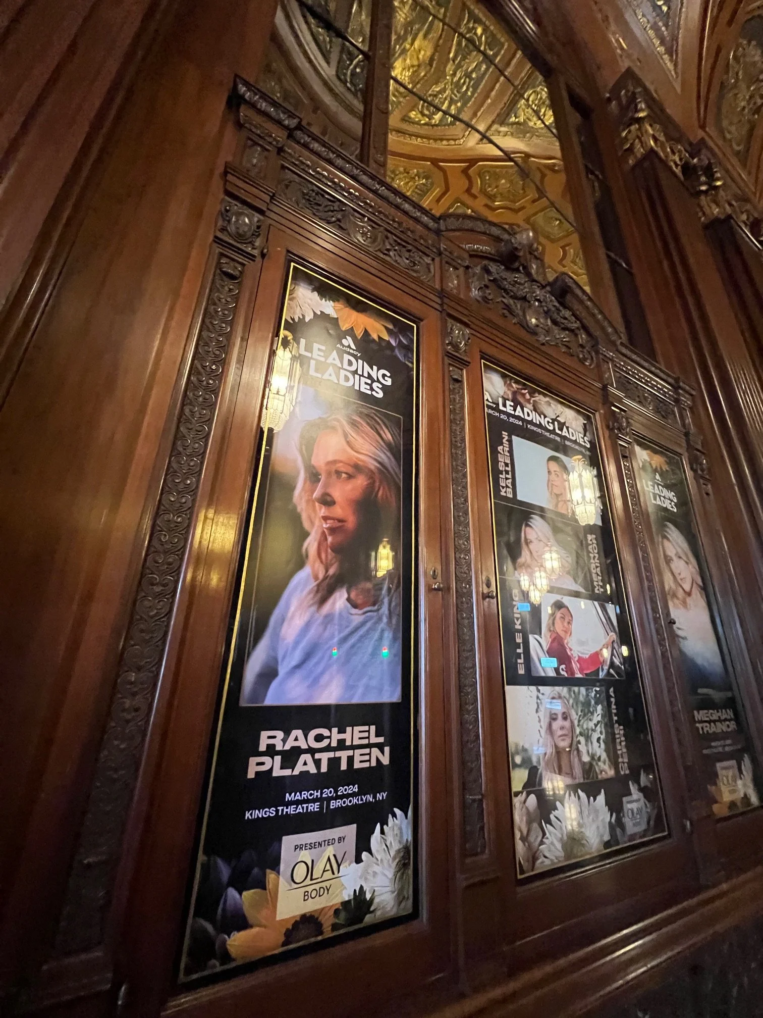 Wooden frame posters of the Broadway show "Leading Ladies" featuring actress Rachel Platten and others, displayed in an ornately decorated theater.