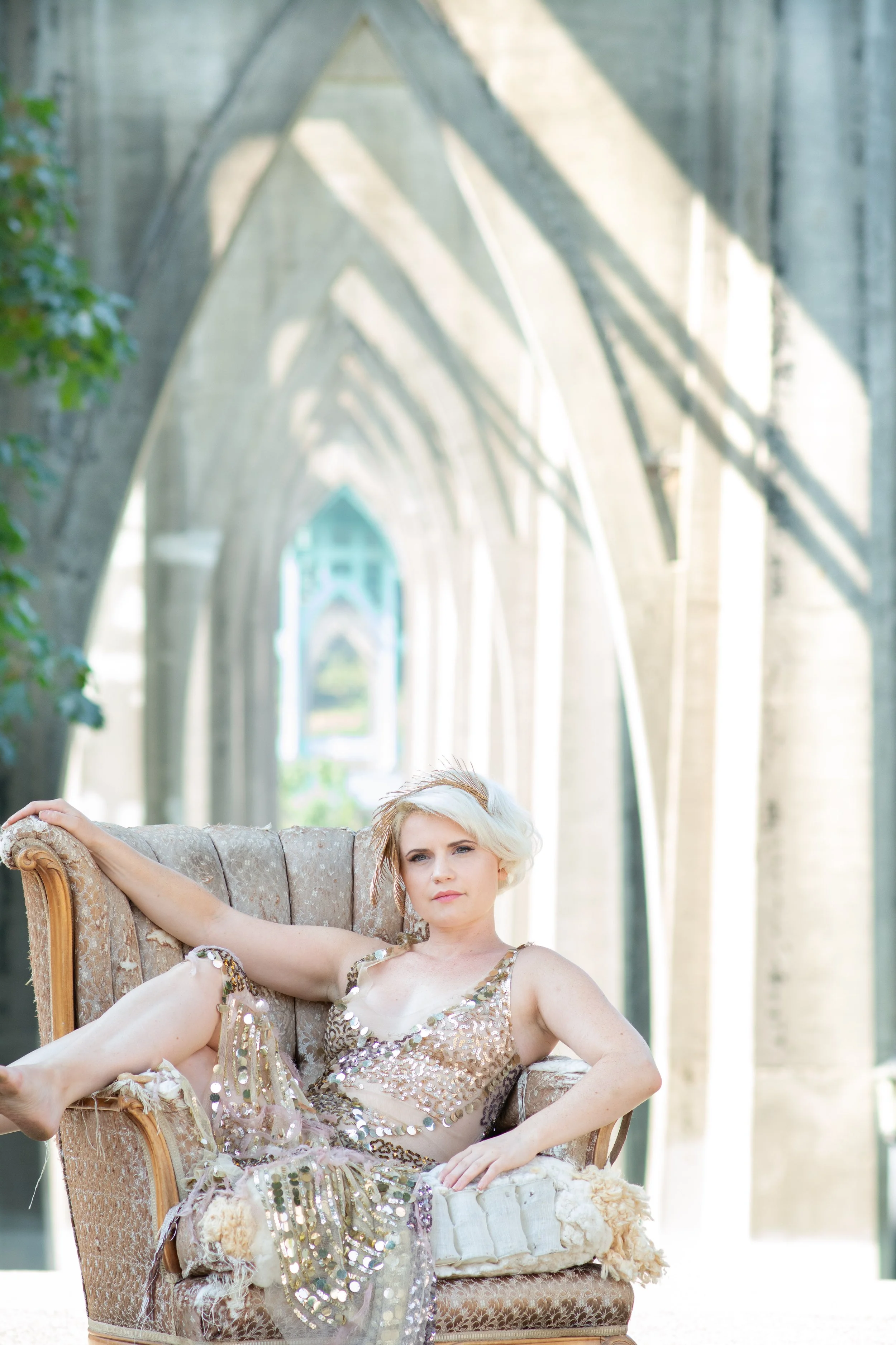 Seattle wedding photographer bride in gold dress reclining in chair under light filled arches editorial portrait Tacoma wedding photographer