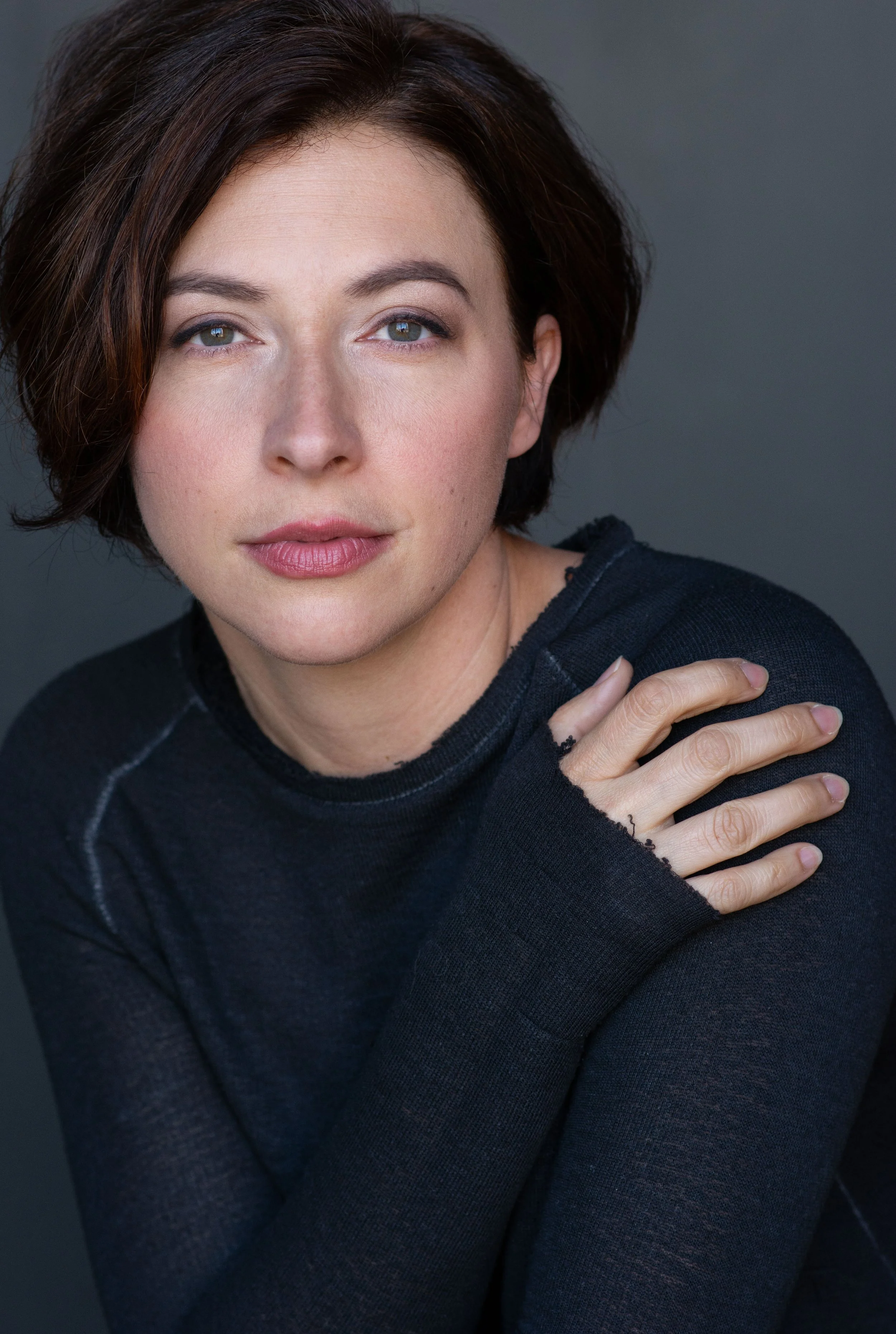 Natural professional headshot of a woman with short dark hair and neutral expression against a gray background in Tacoma, Washington