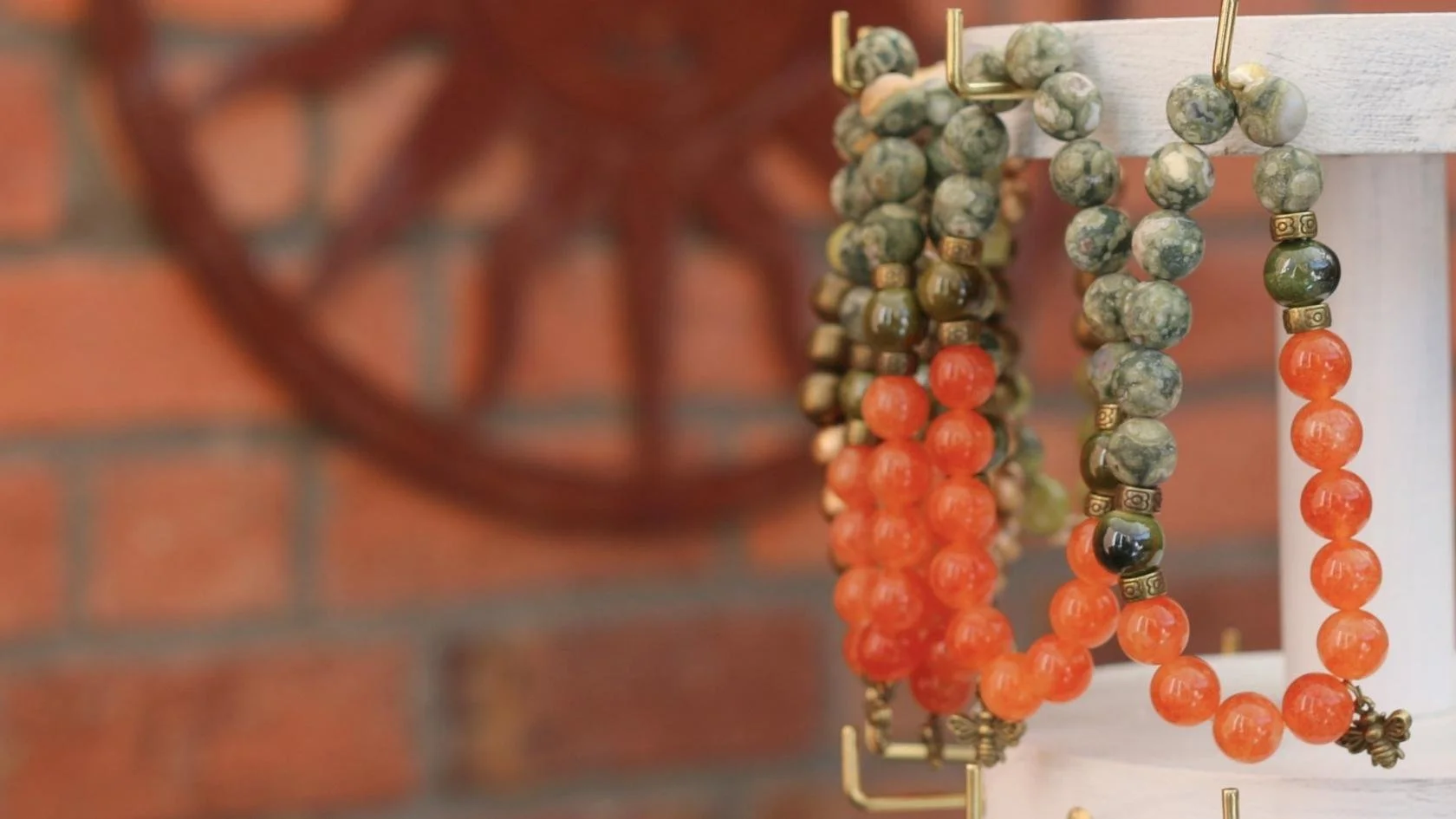 Colorful beaded necklaces hanging on a display rack, with a brick wall in the background.