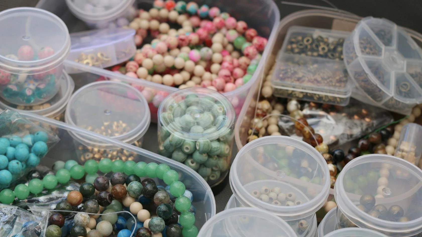Various containers of colorful beads and jewelry-making supplies.