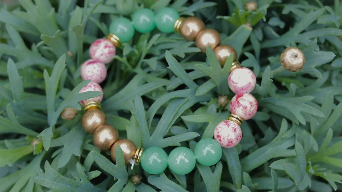 Colorful beaded bracelet resting on green leafy plant.