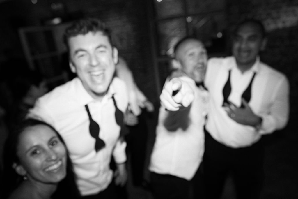 Four people smiling and posing for a photo in a dimly lit indoor setting, dressed in formal attire.