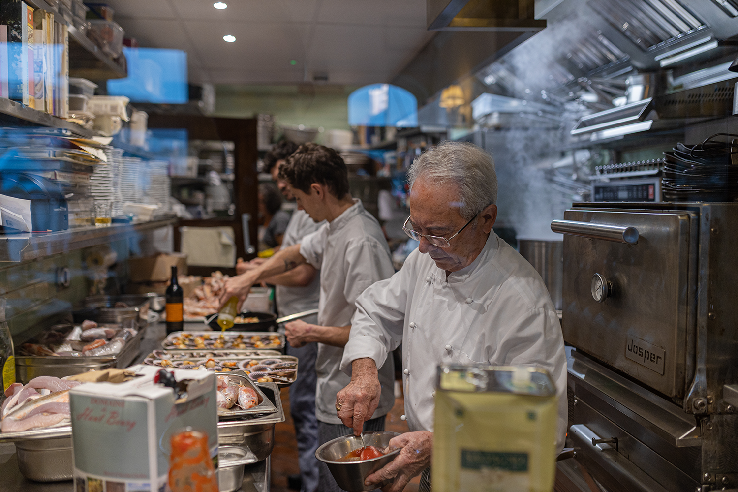 Chefs working in a busy kitchen with seafood and ingredients preparing dishes.