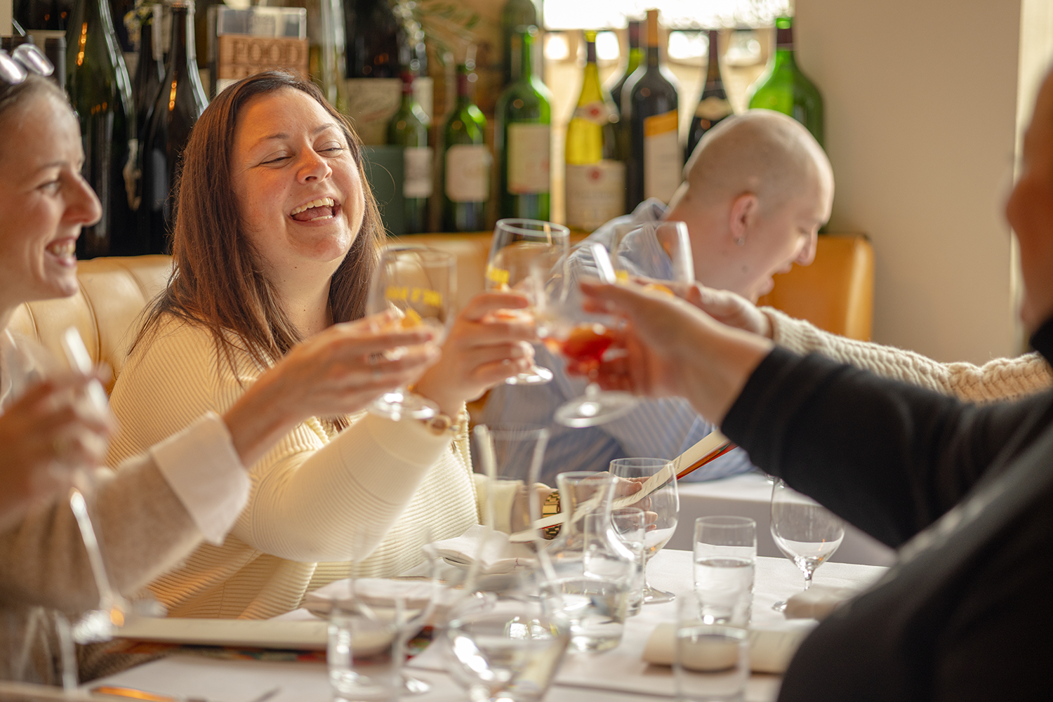 People raising glasses of wine or champagne in a toast during a meal at a restaurant.
