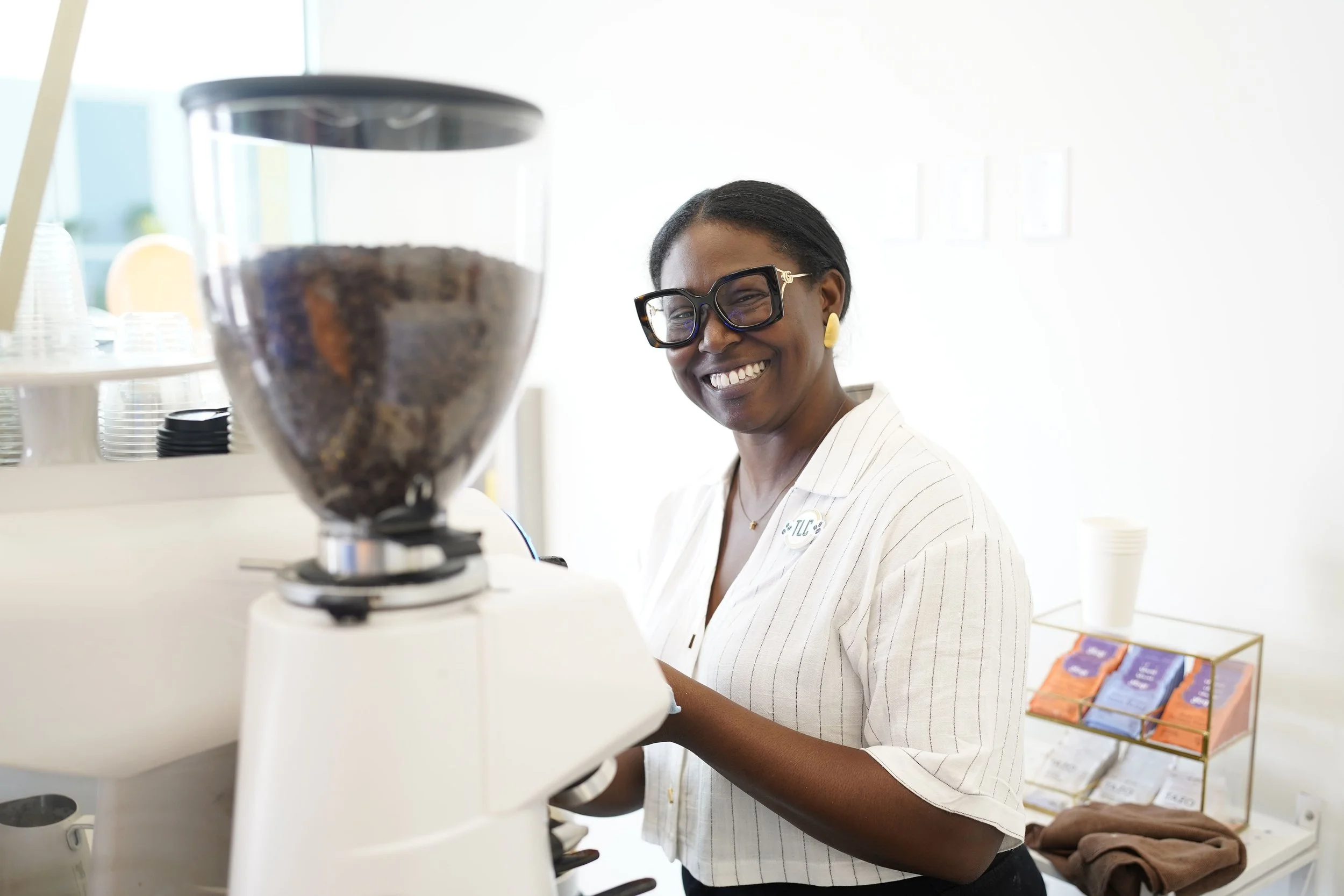Smiling woman with glasses and earrings making coffee or espresso in a coffee shop or cafe.