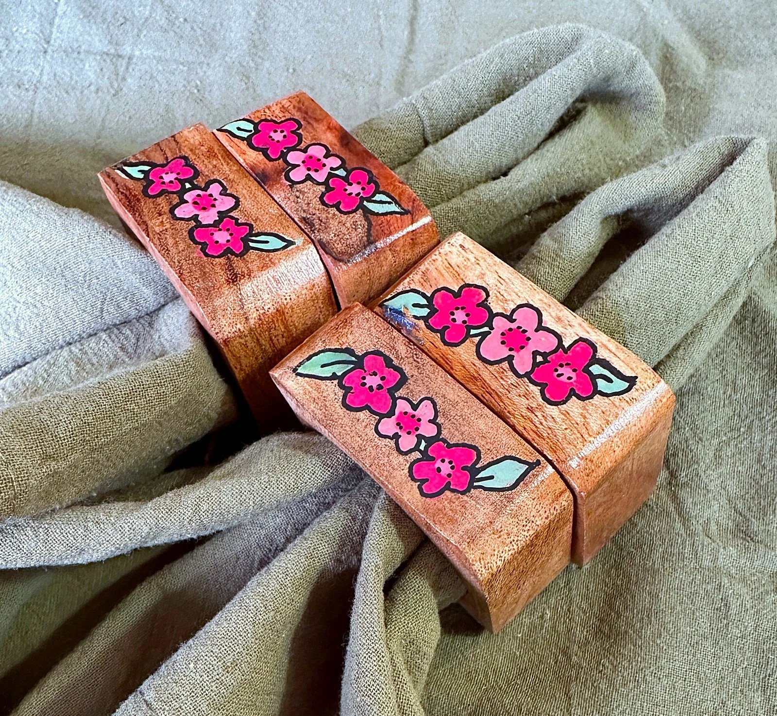 A set of hand-painted wood napkin rings featuring a delicate pink floral motif with soft green leaves.
Part of the Petal & Wing collection — nature-inspired tabletop accents pairing floral and organic details.