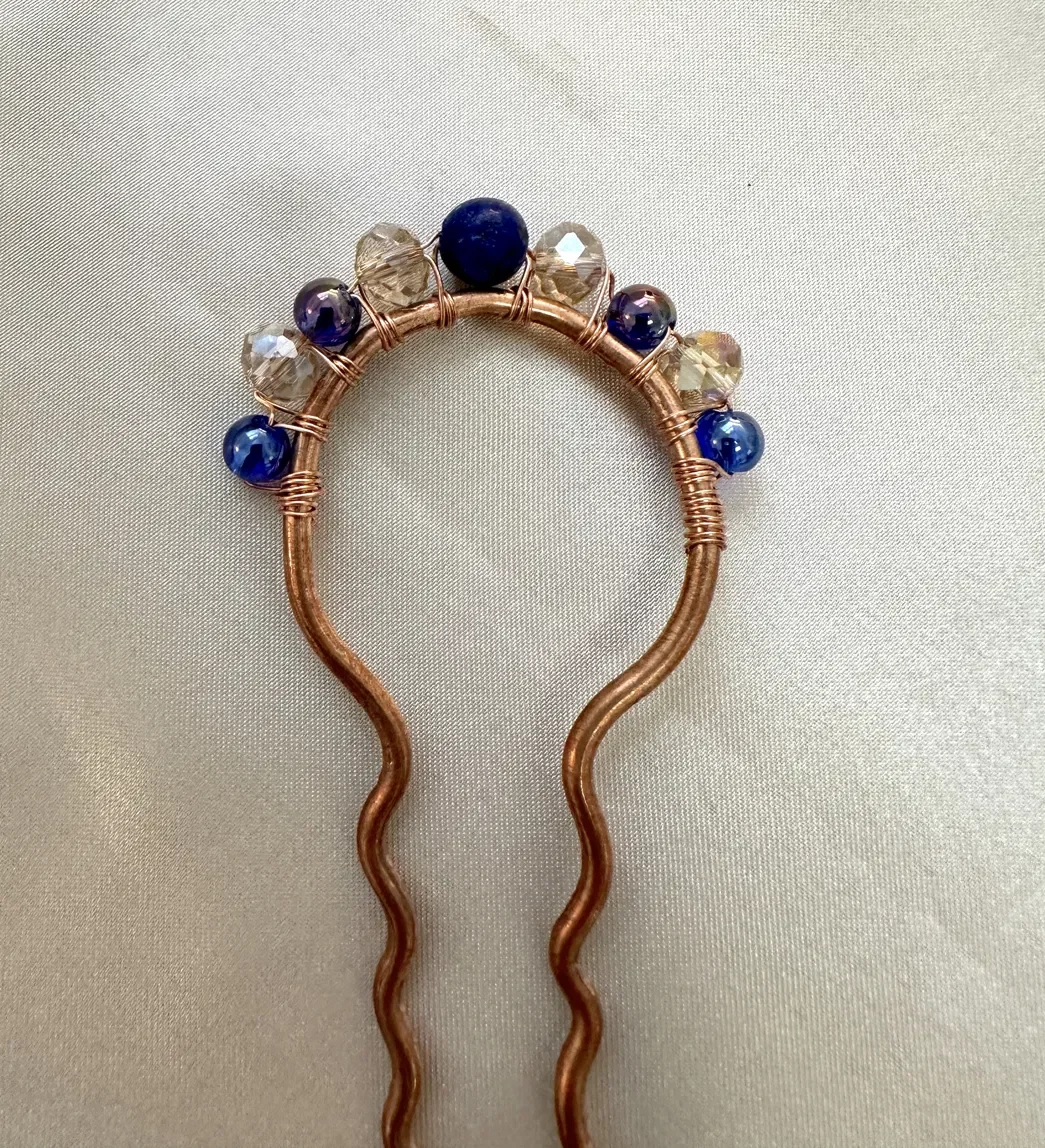 Handmade signature hair pin featuring a hand-formed copper crown set with blue and clear glass beads — part of the Deep Blue Lake collection. Wire-sculpted with hypoallergenic hardware.