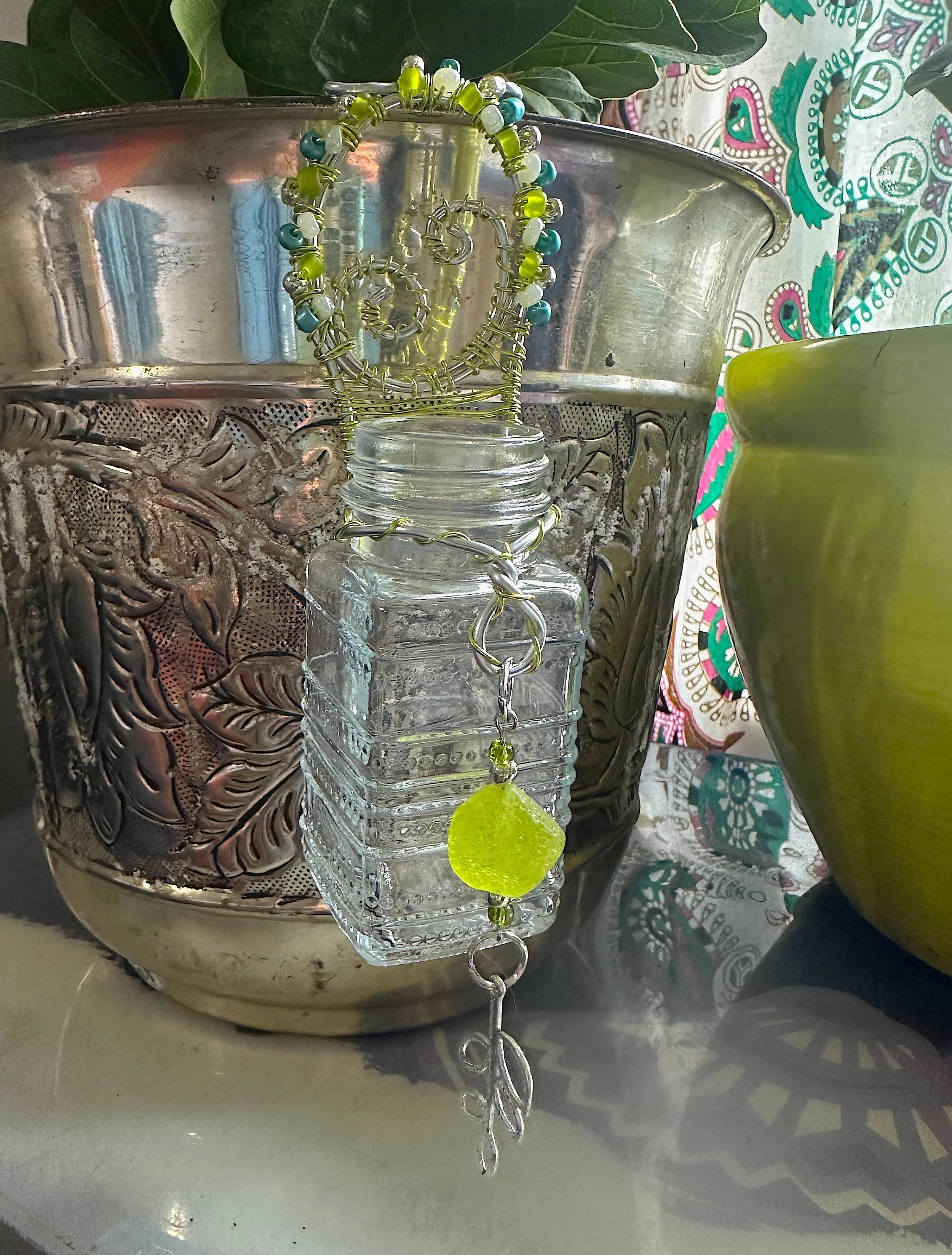 A small glass propagation jar wrapped in green and white beaded wire, perfect for rooting cuttings by a sunny window.
From the Moss Light series — botanical, greenery-inspired pieces for plant lovers.
