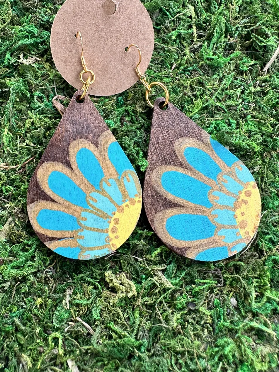 Handmade studio earrings featuring a hand-painted floral design on acacia wood in blue and gold — part of the Bramble and Herb collection. Sealed with a food-safe, non-toxic finish.