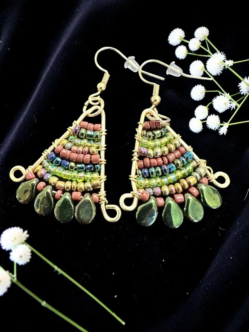 Handmade woven earrings featuring layered seed beads in green, copper, and iridescent tones with beaded glass drop fringe — part of the Woodland Magic collection. Hypoallergenic ear wires, hand-woven bead by bead.