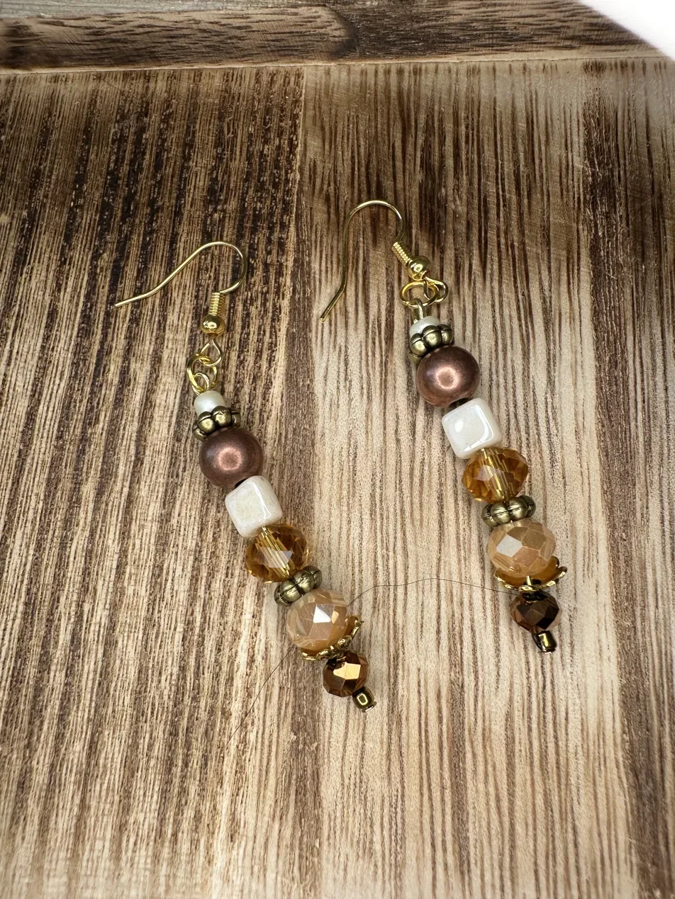 Handmade drop earrings featuring warm gold crystal, copper, and ivory beads — part of the Golden Hour collection. Hypoallergenic ear wires, hand-beaded and finished with gold accents.