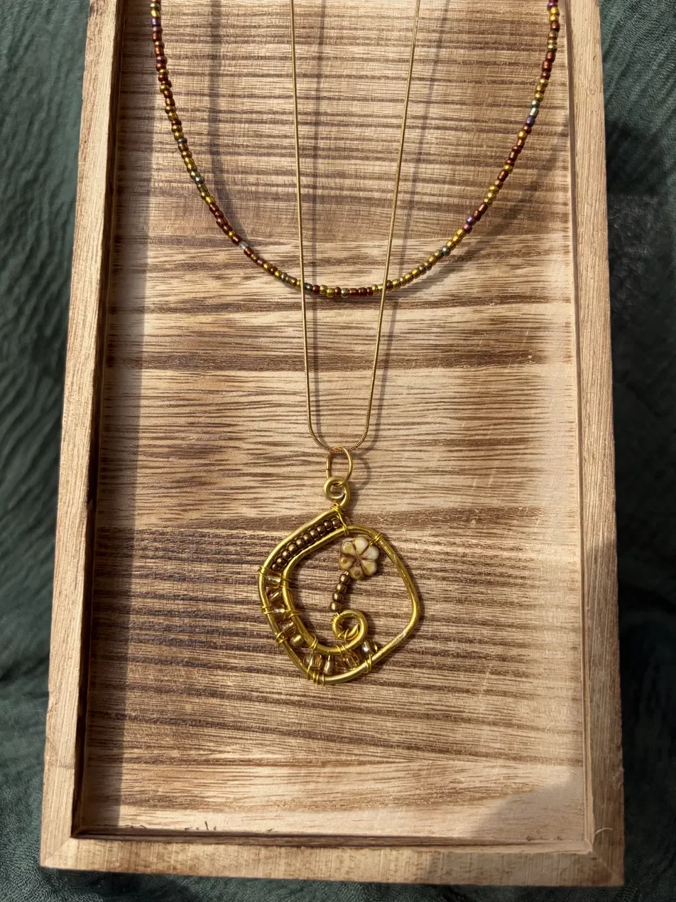 Handmade signature necklace featuring a hand-formed gold pendant with a ceramic flower bead, paired with a beaded seed bead chain and delicate gold layering chain — part of the Golden Hour collection. Hypoallergenic hardware.