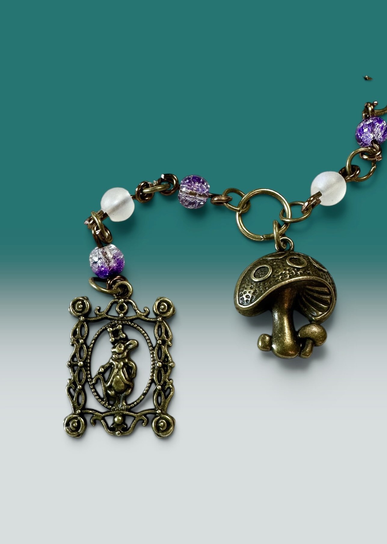 Handmade children's charm set featuring a bronze rabbit-in-frame charm and a mushroom charm with purple and clear glass beads — part of the Hyacinth collection. Hypoallergenic clasp hardware.