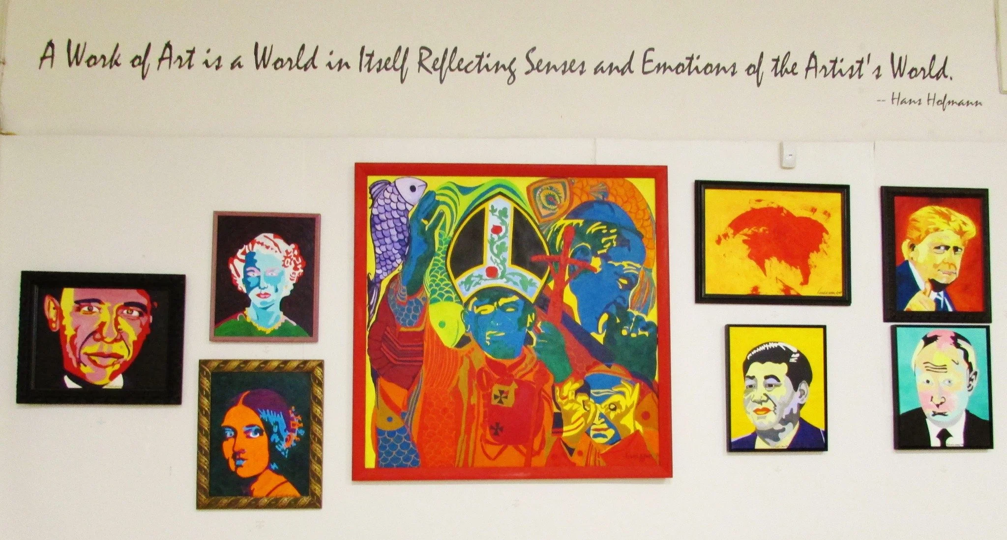 Art gallery wall displaying colorful, pop art portraits of various famous figures, including Barack Obama, Queen Elizabeth, and others, with a quote about art at the top.