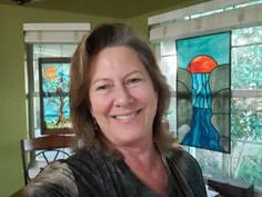Woman smiling in front of colorful stained glass windows