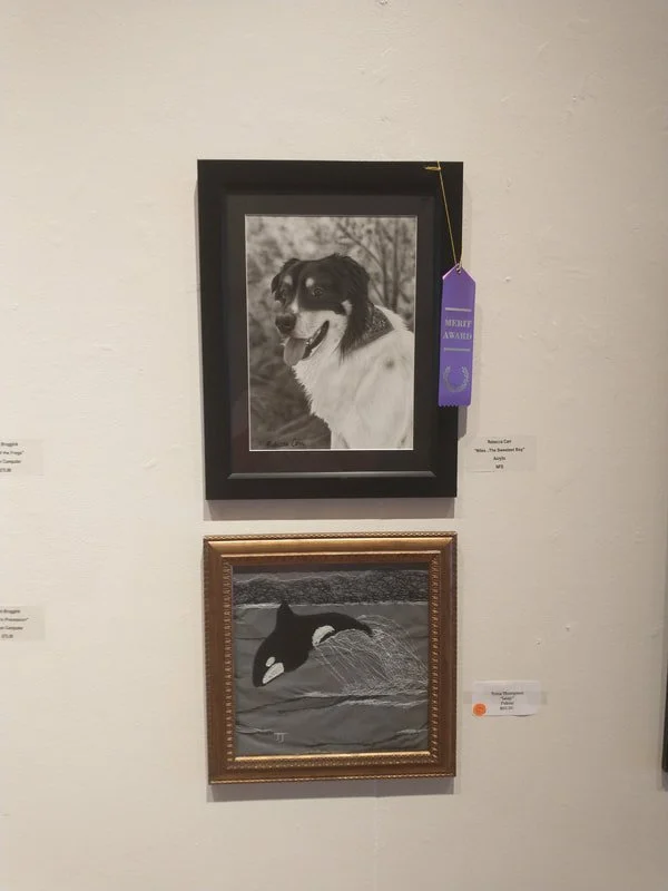 Two framed black and white artworks on a white wall, one of a dog and the other of a bird
