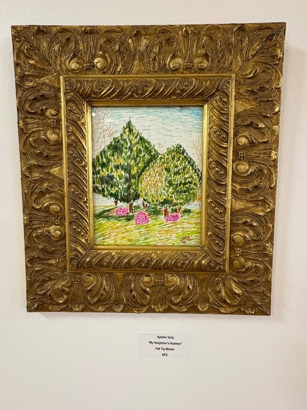 A colorful painting of two green trees with pink flowers underneath, framed in an ornate gold frame, displayed on a white wall.
