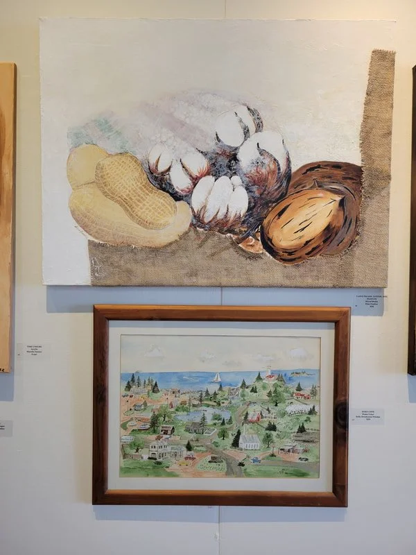 Top painting of cotton, peanuts, and a peanut shell. Bottom painting of a coastal town with houses, trees, a lake, and sailboats.