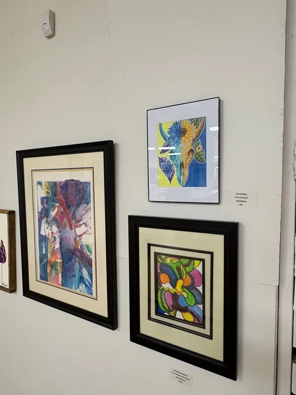 Three framed abstract artworks hanging on a white gallery wall.