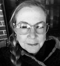 A woman with glasses and braided hair smiling at the camera