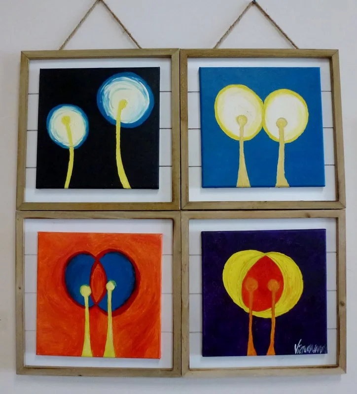 Four abstract paintings of stylized trees with circular yellow tops and yellow trunks, framed in wooden frames, hanging on a white wall.