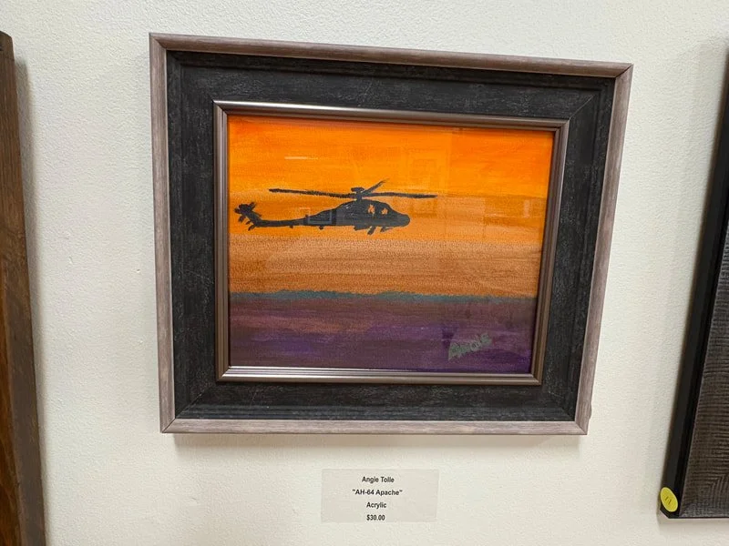A framed acrylic painting of a helicopter flying at sunset or sunrise with an orange, yellow, and purple sky.