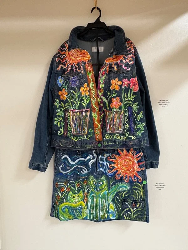 Painted denim jacket and skirt with colorful floral and animal designs, including a large sun, owls, and abstract patterns.