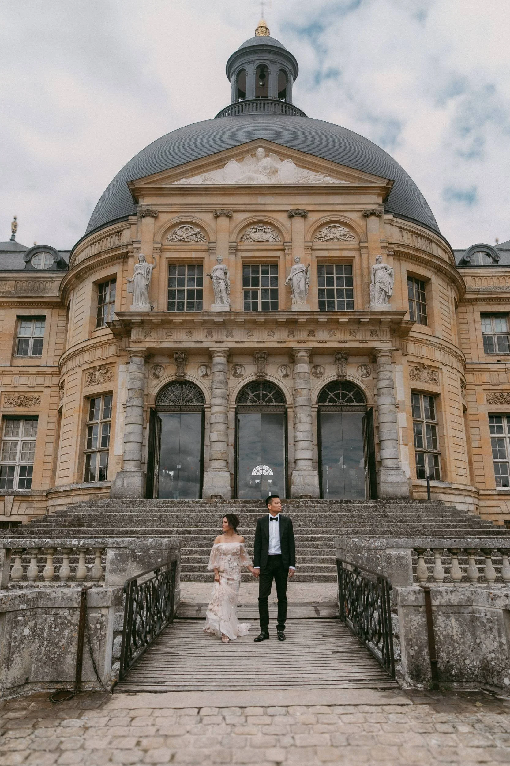 a paris engagement portrait session by destination wedding photographer janine rose of a couple holding hands and looking opposite directions in front of a historic building-polaroid
