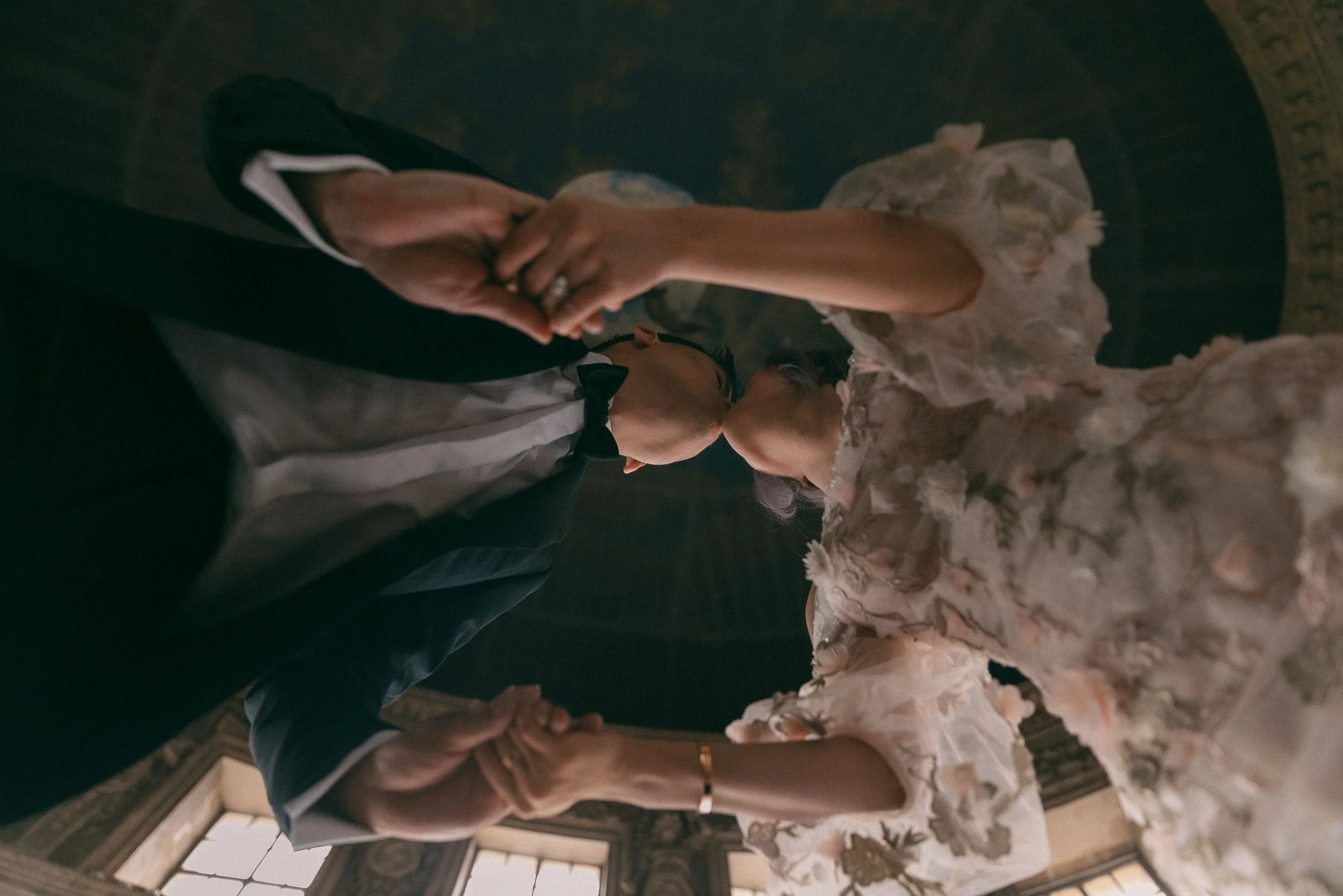 an artistic photo shot from underneath a couple kissing inside of a historic building in Paris