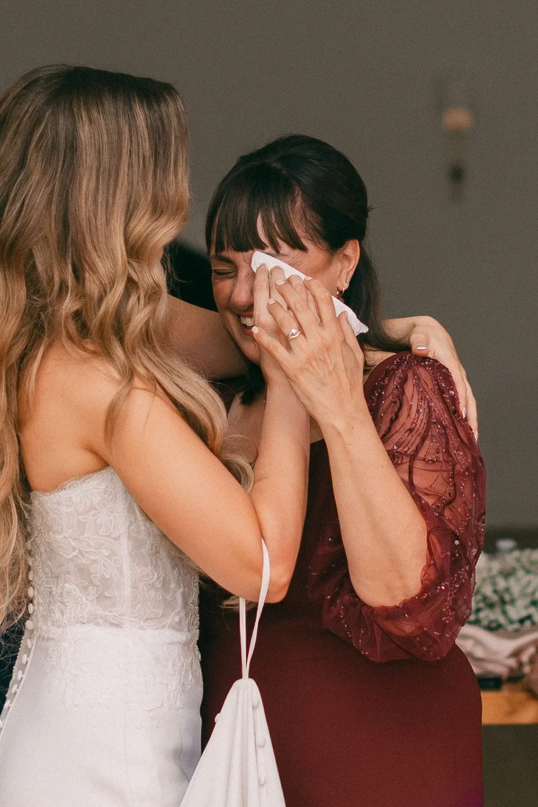 photo of a bride hugging someone in a red dress and wiping her tears with a tissue-polaroid