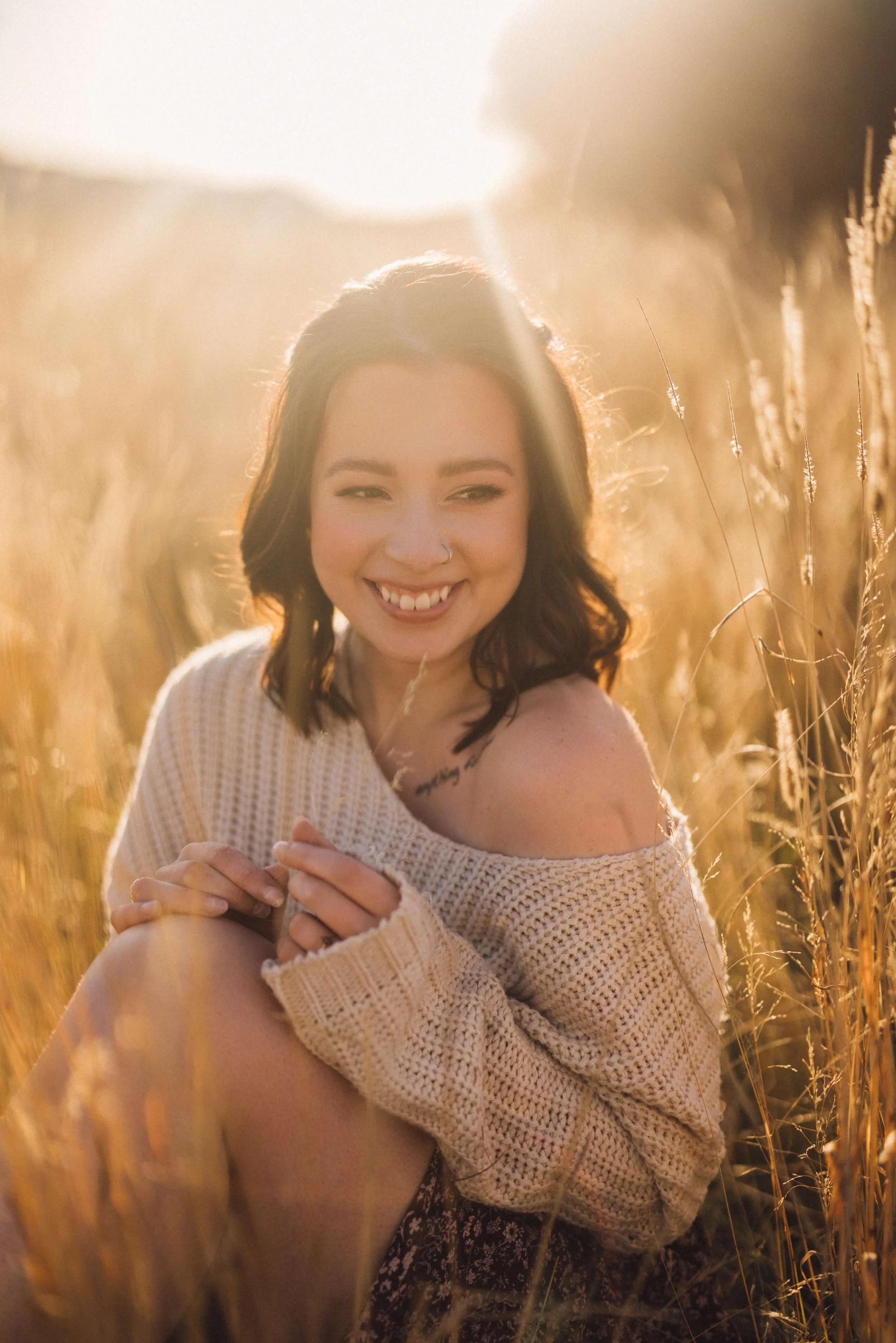 photo of edmonton wedding photographer janine rose sitting in a field and smiling-polaroid