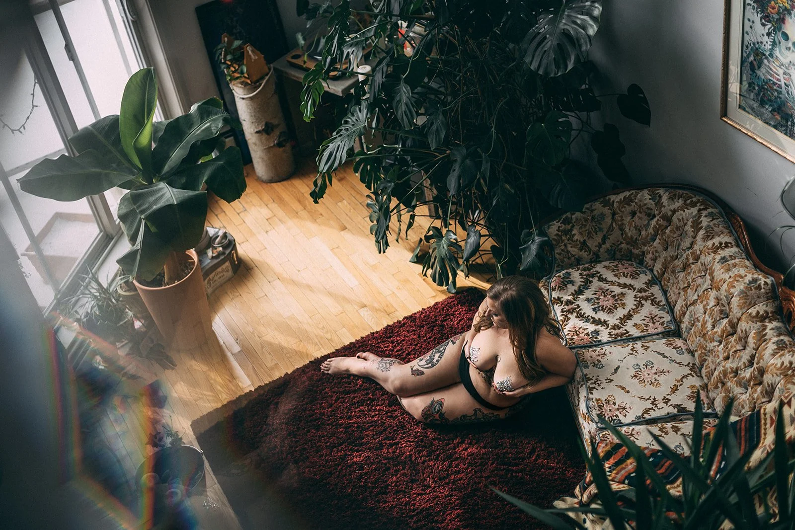 a woman poses on the floor of a plant filled loft
