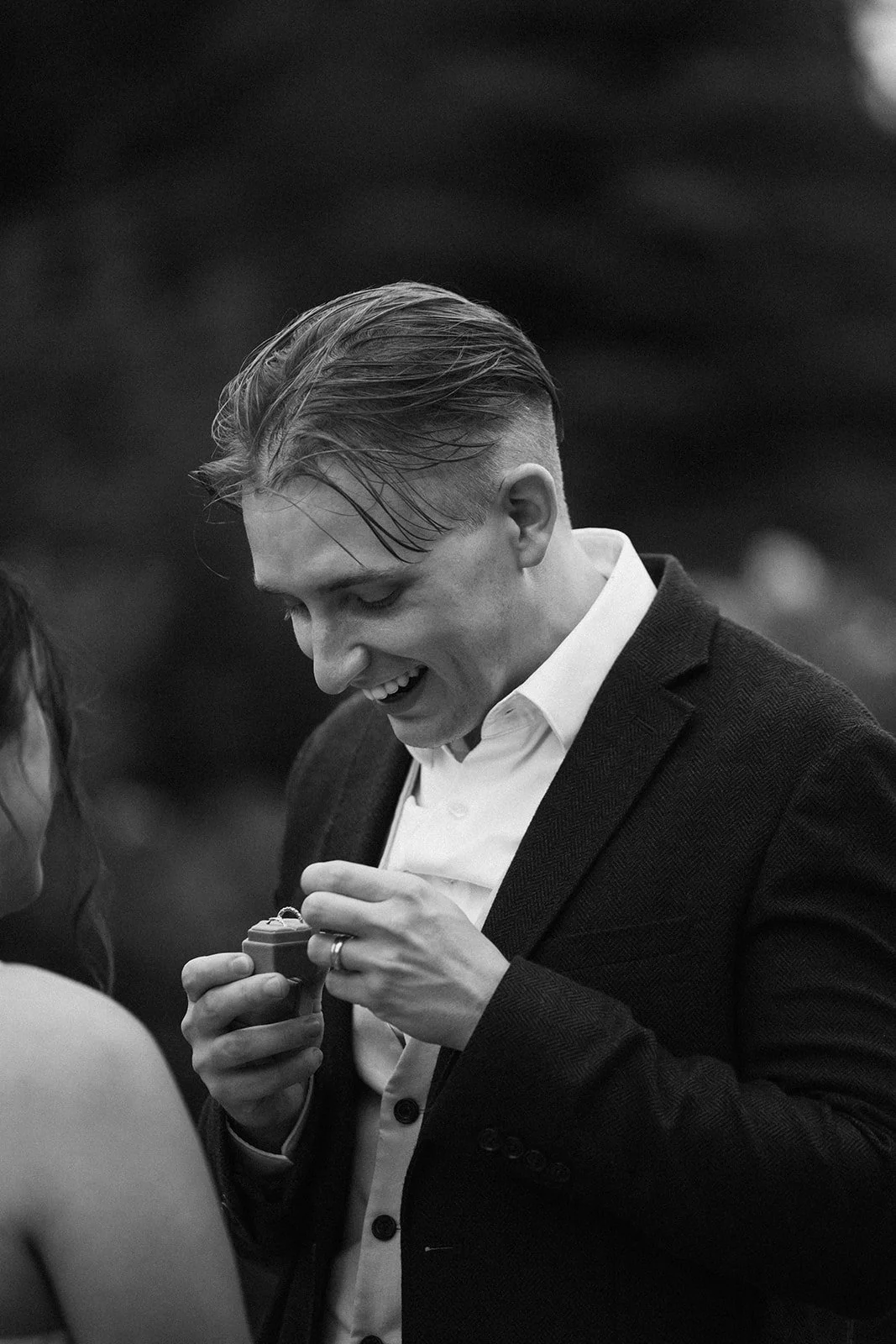 A man opens a gift from his fiancee, his wedding band