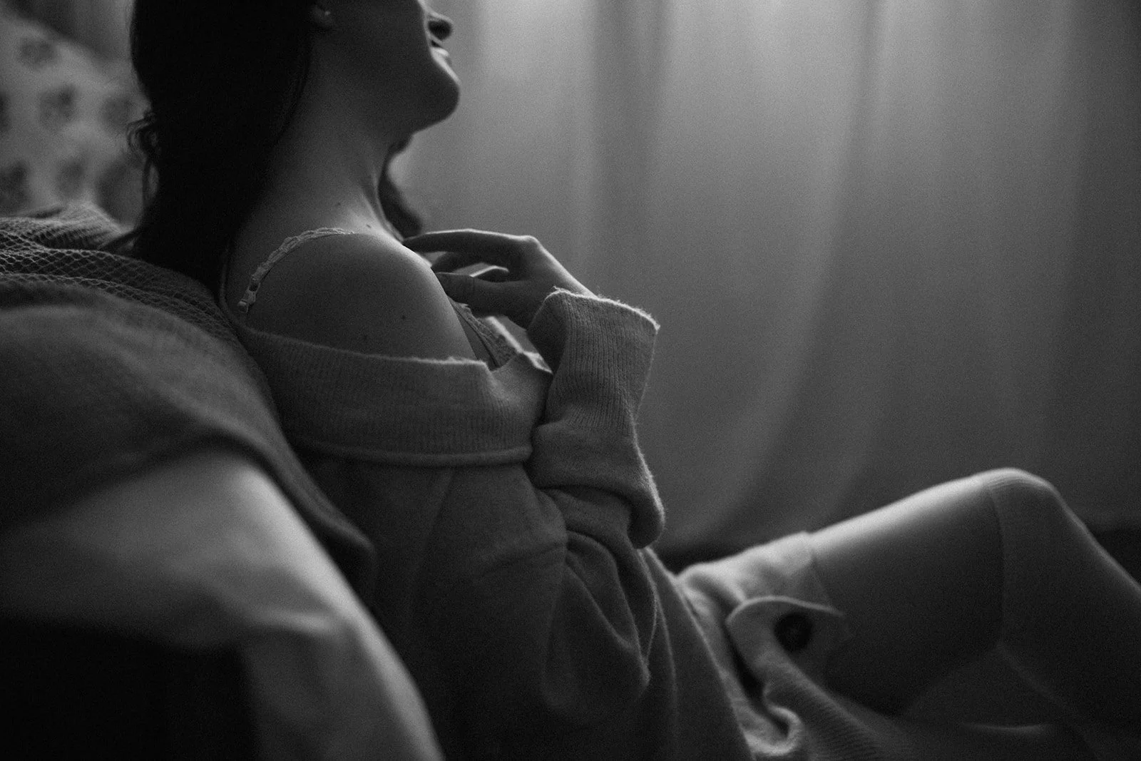 black and white image by edmonton boudoir photographer janine rose of a woman touching her shoulderthin-bordered