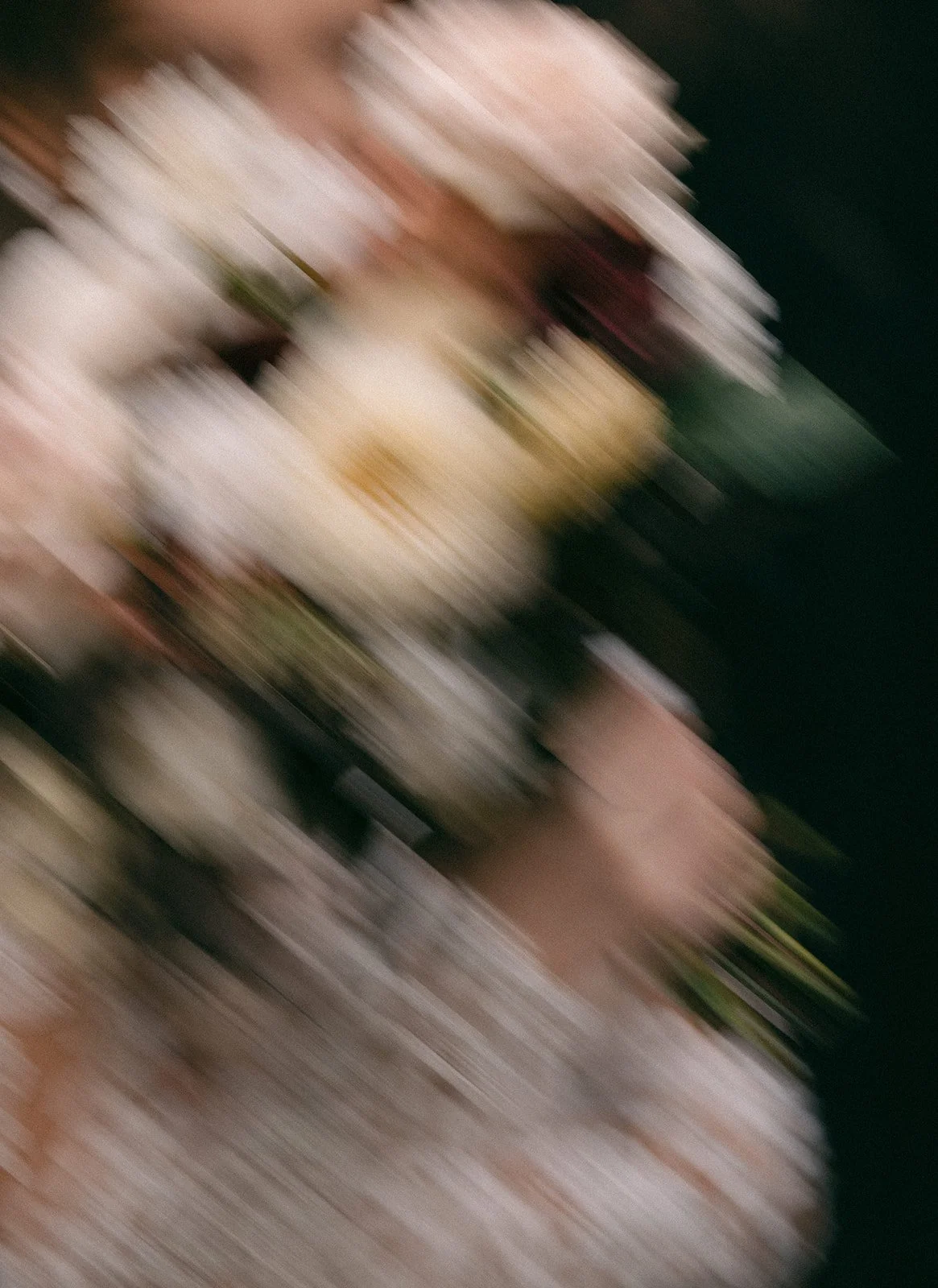 a blur motion photo of a bride holding a moody bouquet of flowers