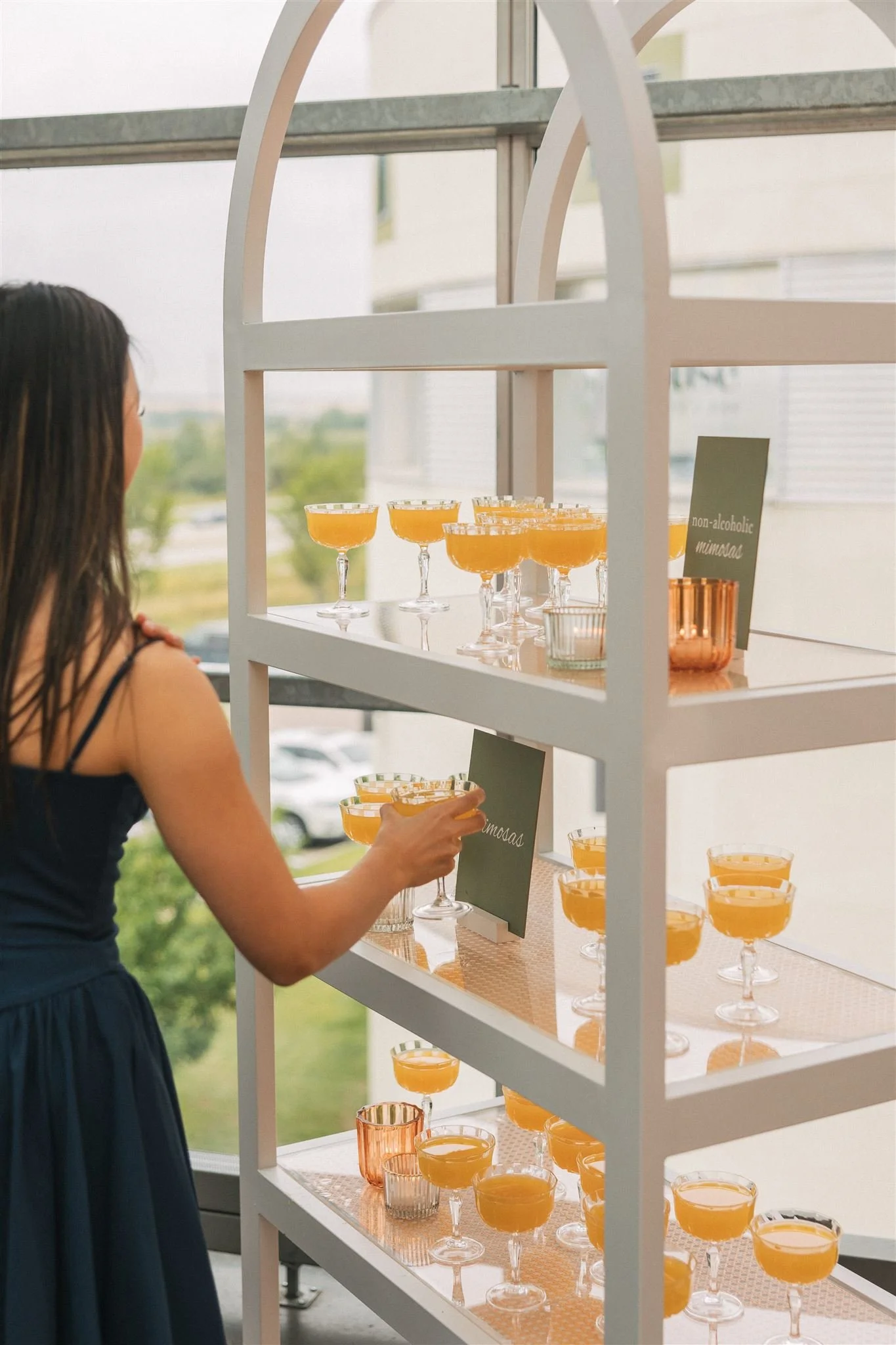 a wedding guest selects a mimosa from a drink display at a brunch wedding