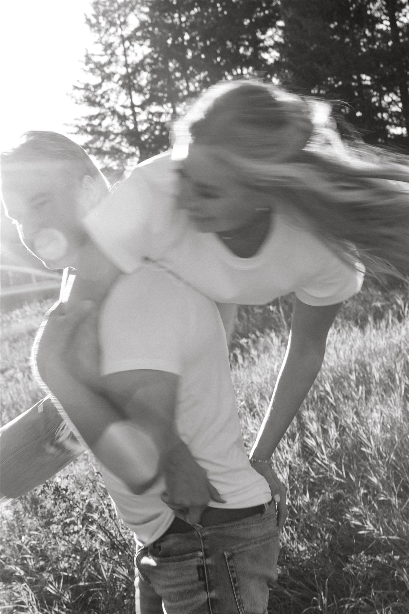 a black and white photo of a man holding his girlfriend over his shoulder while walking in a field-polaroid