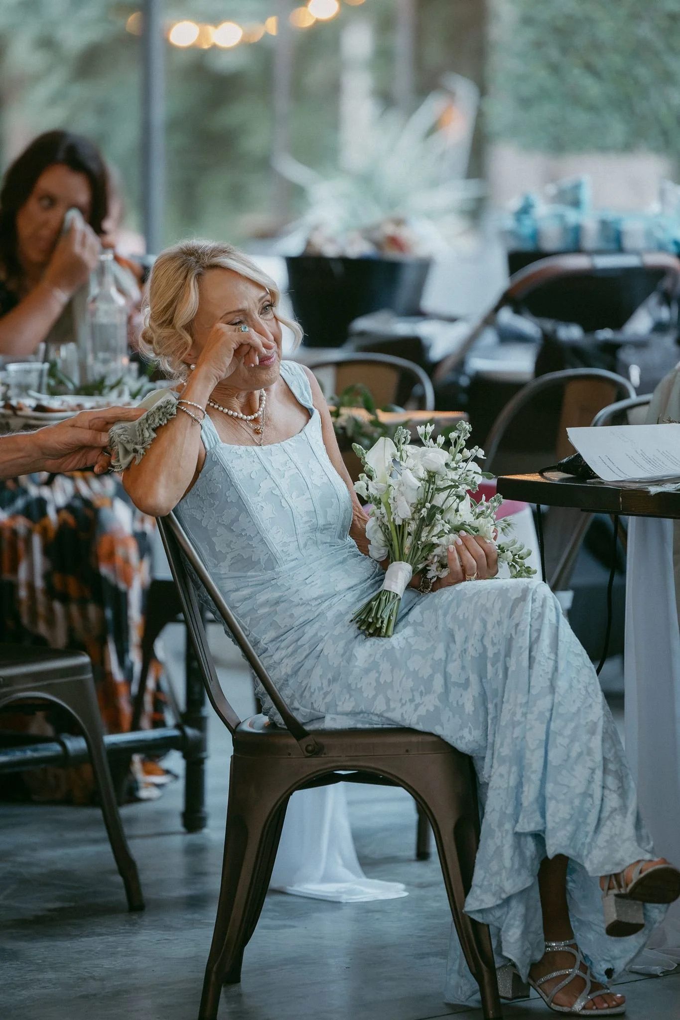 a mother of the bride sitting at the wedding reception watching a speech and wiping tears away - polaroid
