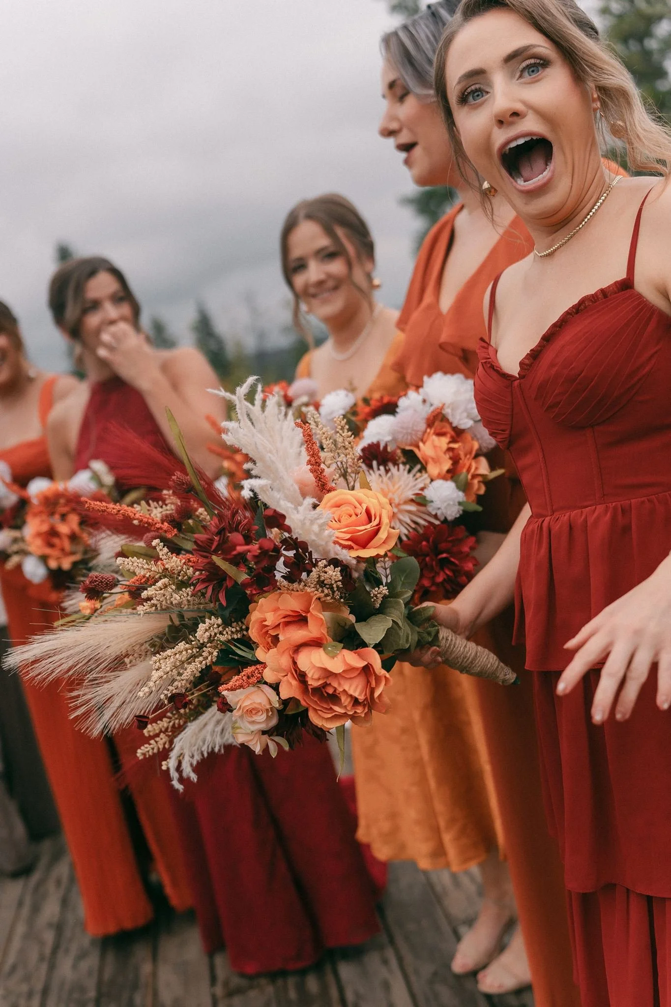 bridesmaids in orange and red dresses smiling at the camera during wedding party photos with Edmonton wedding photographer Janine Rose - polaroid