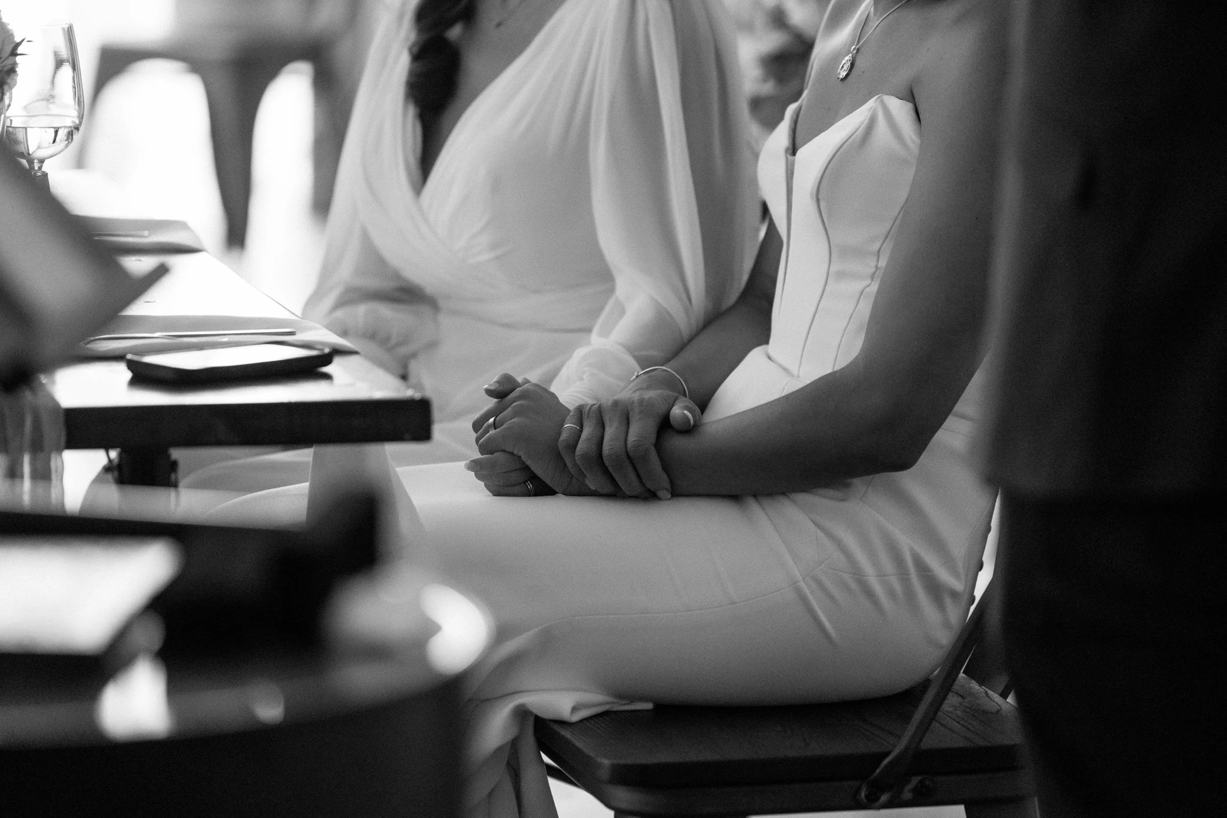 photo of two brides holding hands under the table-thin-bordered