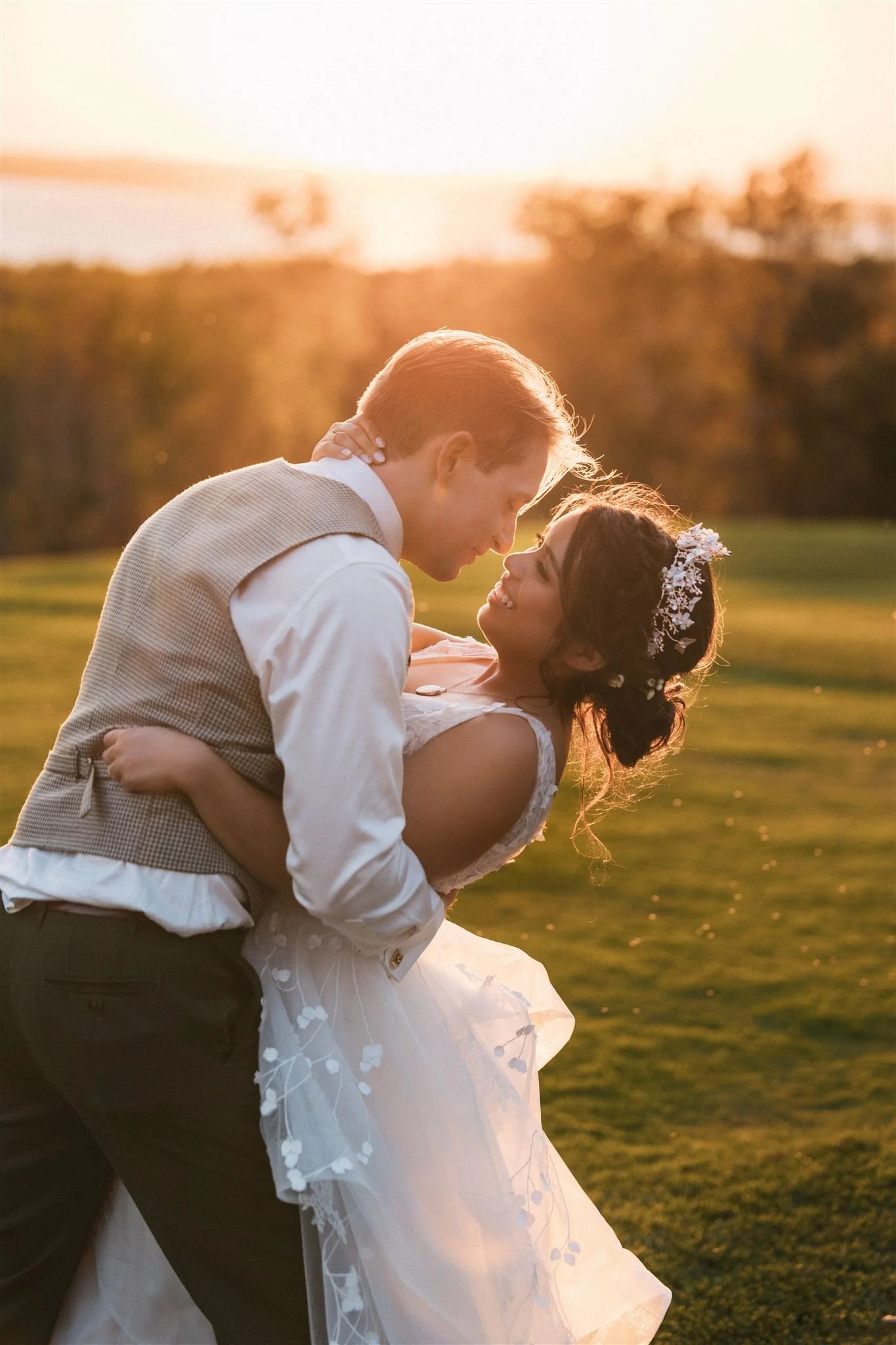 wedding portrait of a bride and groom embracing in a green field at golden hour