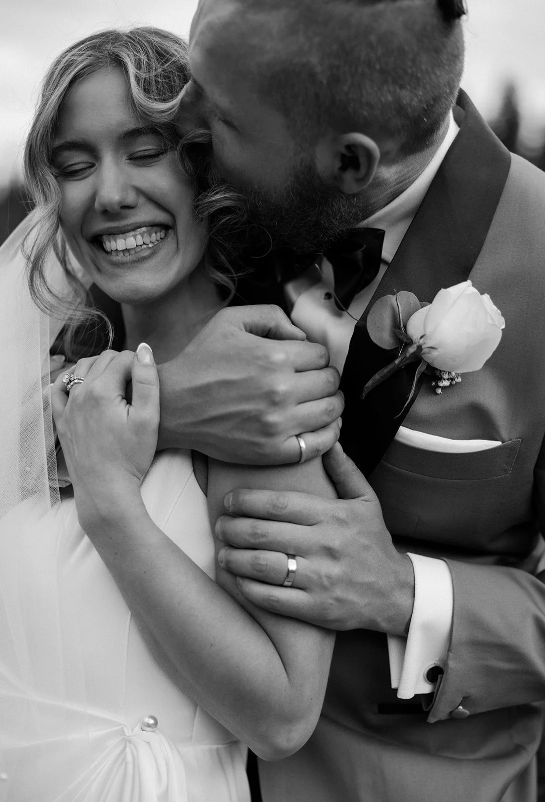 a black and white photo of a groom kissing his bride on the cheek-polaroid