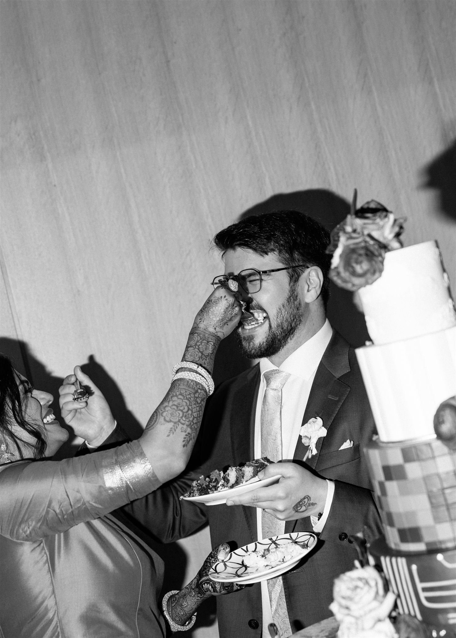 a bride and groom feeding each other a first bite of wedding cake-bordered