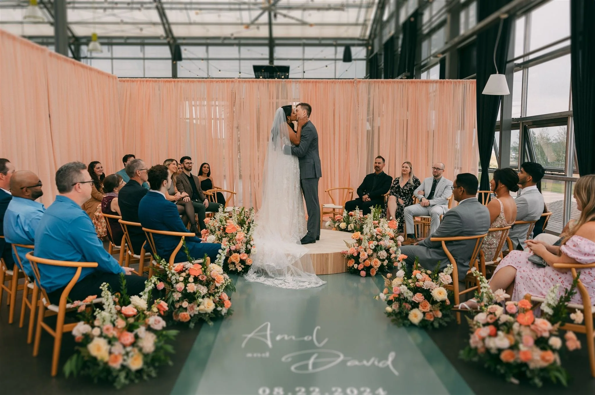 A couple shares their first kiss at the intimate ceremony, up on a wood platform surrounded by a circle of their family and friends