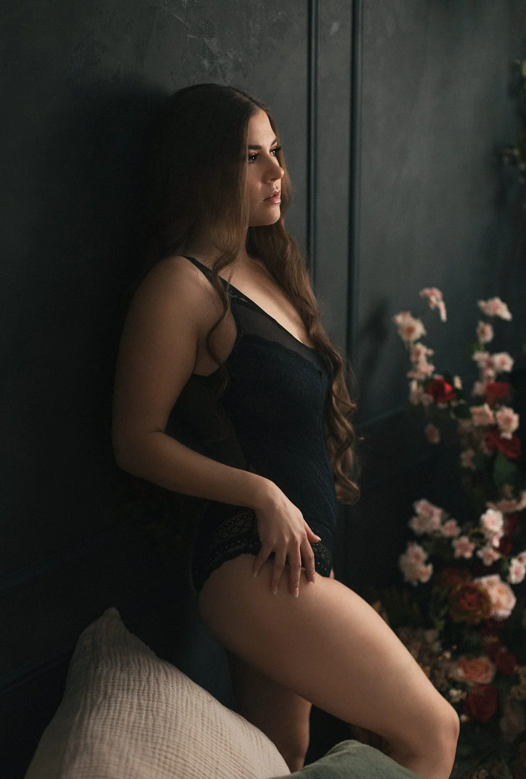 boudoir photo of a woman leaning against a black wall with flowers in the background-sticky