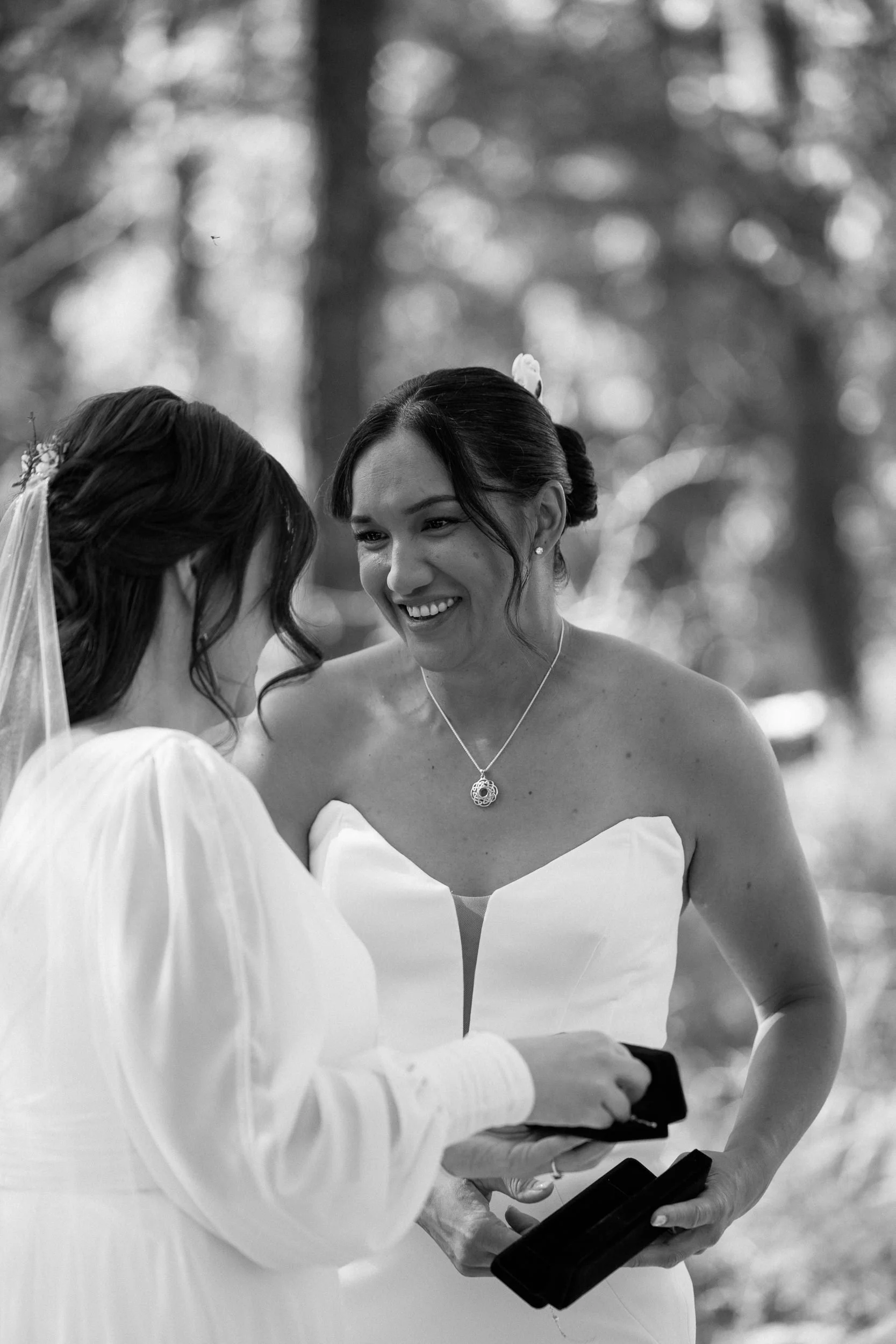 black and white portrait of two brides smiling at each other-thin-bordered