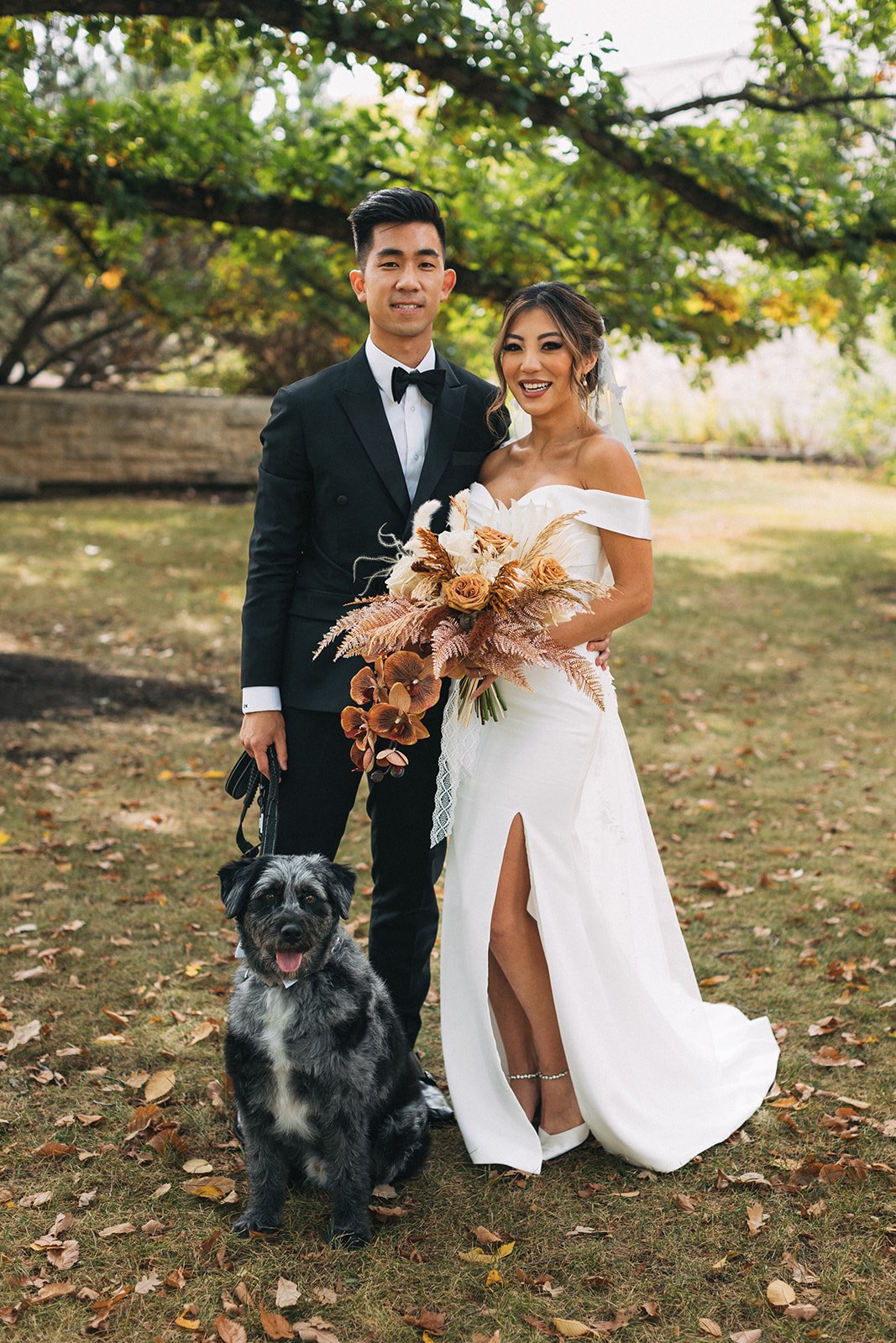A couple in their wedding attire poses with their dog